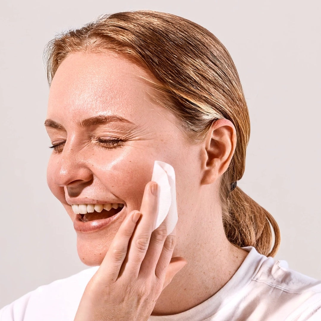 Smiling model pressing a white toner pad against their cheek